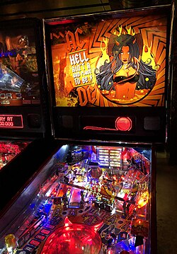 Pinball machine in the style of AC/DC. The artwork shows the AC/DC logo in between the words "Hell Ain't a Bad Place to Be" with the logo's high voltage symbol at the beginning and end of the words, and a hand-drawn woman with black hair, devil horns and a black bikini, standing in lava with fire in the background.