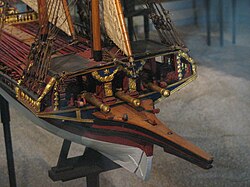 The bow of a ship model focused on a raised platform with cannons underneath