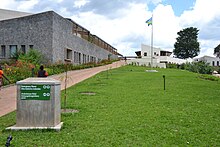 Photograph depicting a hospital building, with Rwandan flag, viewed from the entrance pathway