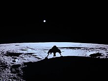 The shadow of the Blue Ghost lander is seen on the bottom of the image, as the surface of the Moon spans the lower half, a pale blue circle in the upper area of the image is Earth.