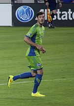 Man in green uniform running on field.