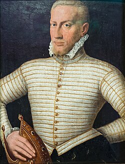 A blond-haired man stands with his left hand on his hip, and his right hand holding his bishop's mitered hat. He is wearing a high-collared waist coat with pleats and many buttons. The high collar has a lace ruffle. He has a short beard and mustaches; his hairline is receding.