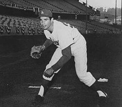 "A man in the Los Angeles Dodgers home uniform and cap with a glove, posing in fielding position."