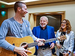 Martin talking with another man and woman while holding a guitar