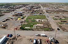 A row of homes amidst streets are seen obliterated with volunteer vehicles lining the streets. The photo is taken from an aerial vantage point.
