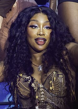SZA on stage smiling while looking at a crowd