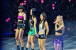 Blackpink standing onstage, facing leftwards