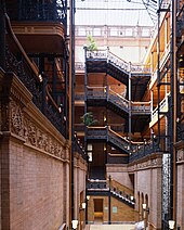 A photograph of a building interior showing stairs climbing up five storeys to the final floor where we can see the glass roof