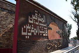 Monument on the mosque's west side featuring Quranic verse 55:17.