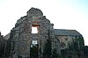 Stone wall with window of ruined building.