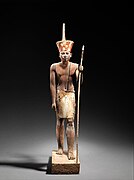 A guardian statue wearing the red crown which reflected the facial features of the reigning king, probably Amenemhat II or Senwosret II, and which functioned as a divine guardian for the imiut; made of cedar wood and plaster c. 1919–1885 BC[7]