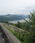 Sweeping photograph of the Columbia River Gorge from Crown Point, Oregon, with a segment of the Columbia River Highway traversing a steep cliff face in the foreground.