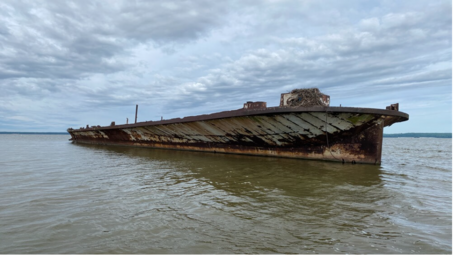 Starboard bow view of a shipwreck in shallow water