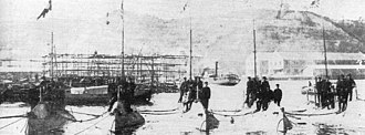 Five submarines moored next to each other with men standing on them