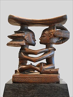 Headrest; 19th century; wood; height: 18.5 cm (7.3 in), width: 19 cm (7.5 in), thickness: 8 cm (3.1 in); Musée du quai Branly (Paris). This headrest presents 19th century Luba hairstyles, as well as the long limbs, bent-back legs, cylindrical torso and dynamic pose typical of the artist who made it.