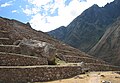 Workers are dwarfed by terraces, which are in turn dwarfed by the surrounding mountains