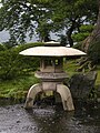 Three legged yukimi-dōrō. One leg rests on ground, two in water.