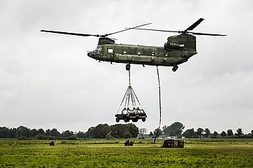 A Dutch CH-47D hauls slung light vehicles and a load on exercises, 2015