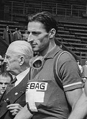 Black-and-white image of a man in a shirt with a cross.