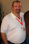 Half-length view of a Caucasian man in a striped shirt.