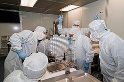 An investigator flashes V-for-victory signs upon the 2006 arrival of material gathered by the Stardust spacecraft at the Johnson Space Center in Texas.