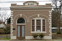 A one-story brick building with taupe paint and the word "BANK" on the top.