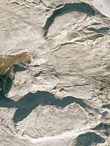 An overhead view of two flat-topped, steep-sided rocky hills on a barren surface.