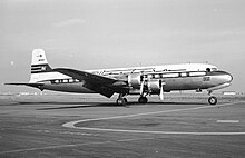 A black-and-white photograph of a four-engine aircraft at an airport