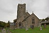 Stone building with square tower. In the foreground are gravestones.