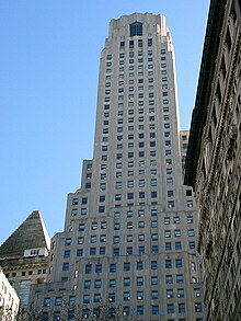 One Wall Street as seen from Rector Street to the west. The pyramidal roof of 14 Wall Street is visible at left, while the Empire Building is visible at right.