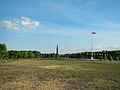 The flag at the shrine foregrounding the shrine's obelisk in the distance.