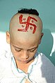 A Hindu child with a shikha and a red swastika painted on his head.