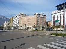 Car square with a six-storey, ochre-coloured art deco building.