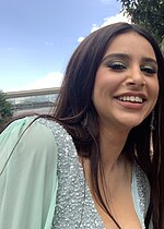 Woman with brown hair wearing a mint green dress smiling towards the camera.