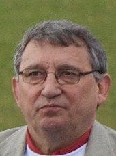 Head of a white man in late middle age with greying hair and wearing spectacles