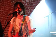 Charlotte Hatherley performing onstage playing and singing into a microphone