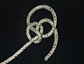 The working end is led around the edge of the underhand knot, and through the loop of the noose