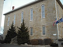 A stone building can be seen from the street, with a flagpole next to it; this was one of the buildings at Lane University in Lecompton, Kansas