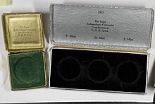 Two clamshell holders for half-dollar coins, one green with a single slot and one black with three slots.