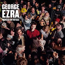 George Ezra is looking towards the camera, standing in the centre of a crowded room. His name and the album title are in the top corner, in large white lettering.