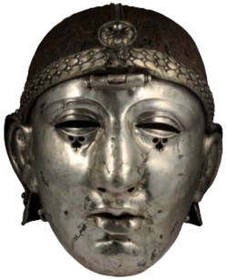 Colour photograph of the Emesa helmet, which has a silver face mask shaped like a human face, and an iron headpiece. The headpiece is decorated with a laurel-wreath diadem and a rosette, and has a central hinge holding the face mask.